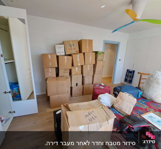 חדר עם קופסאות קרטון, מזוודות וארון פתוח
